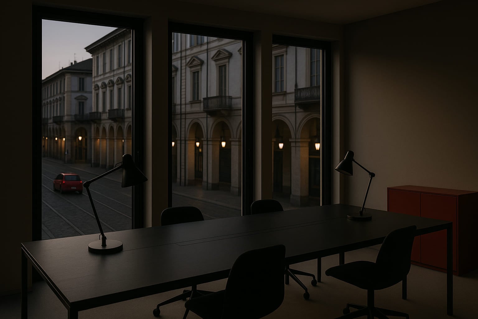 L'interno di uno studio professionale al tramonto: un tavolo lungo e scuro e le vetrate su una via cittadina
